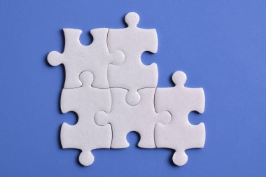 Mavi arka planda beyaz yapboz parçaları. Düz yatıyordu. Üst görünüm