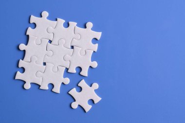 Mavi arka planda beyaz yapboz parçaları. Metin için boşluk kopyala, üst görünüm.