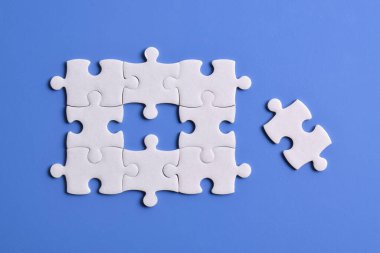 Mavi arkaplanda beyaz yapboz parçaları, üst görünüm