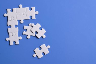 Mavi arka planda beyaz yapboz parçaları. Metin için boşluk kopyala, üst görünüm.