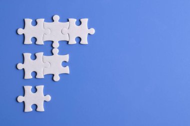 Mavi arka planda beyaz yapboz parçaları. Metin için boşluk kopyala, üst görünüm.