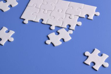 Mavi arkaplanda beyaz yapboz parçaları, üst görünüm