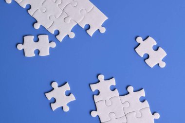 Mavi arkaplanda beyaz yapboz parçaları, üst görünüm