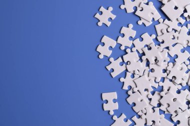 Mavi arka planda beyaz yapboz parçaları, üst manzara. Metin için boşluk