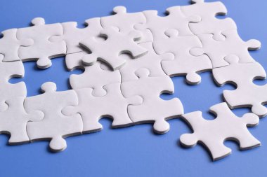 Mavi arkaplanda beyaz yapboz parçaları, üst görünüm