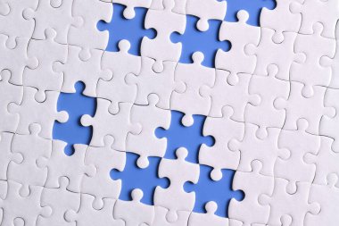 Mavi arkaplanda eksik parçalı beyaz bulmaca, üst görünüm