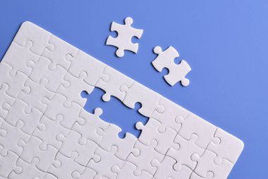 Mavi arka planı eksik olan beyaz bulmaca. Düz yatıyordu. Üst görünüm