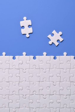 Mavi arka planda beyaz yapboz parçaları. Düz yatıyordu. Üst görünüm