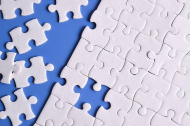 Mavi arka planda beyaz yapboz parçaları. Düz yatıyordu. Üst görünüm