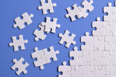 Mavi arka planda beyaz yapboz parçaları. Düz yatıyordu. Üst görünüm