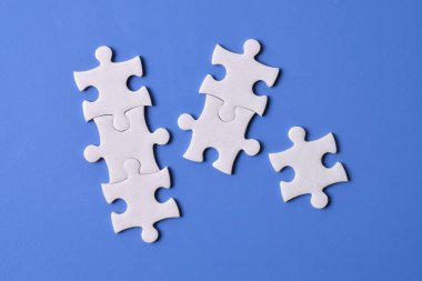 Mavi arkaplanda beyaz yapboz parçaları, üst görünüm