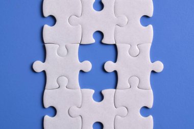 Mavi arka planda beyaz yapboz parçaları. Düz yatıyordu. Üst görünüm