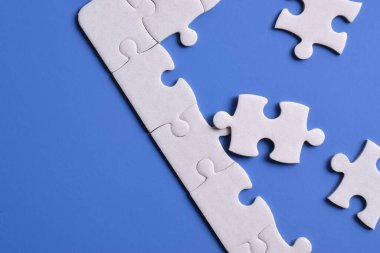 Mavi arka planda beyaz yapboz parçaları. Düz yatıyordu. Üst görünüm