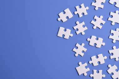 Mavi arka planda beyaz yapboz parçaları, üst manzara. Metin için boşluk