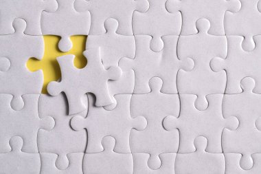 Kayıp yapboz parçaları ve sarı arka planda iş konsepti. Son görev tamamlanıyor