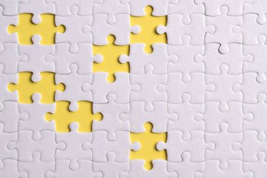 Sarı arkaplanda eksik parçalı beyaz bulmaca, üst görünüm