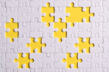 Sarı arkaplanda eksik parçalı beyaz bulmaca, üst görünüm
