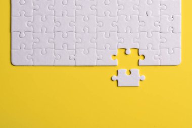 Sarı arka planda beyaz yapboz parçaları. Düz yatıyordu. Üst görünüm