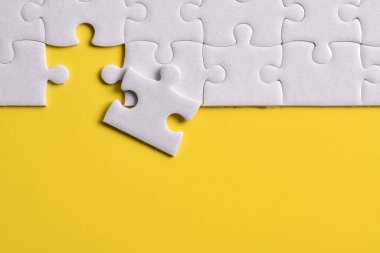 Sarı arka planda beyaz yapboz parçaları. Düz yatıyordu. Üst görünüm