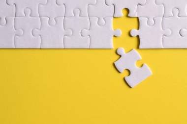 Sarı arka planda beyaz yapboz parçaları. Düz yatıyordu. Üst görünüm