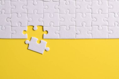 Sarı arka planda beyaz yapboz parçaları. Düz yatıyordu. Üst görünüm