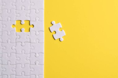 Sarı arka planda beyaz yapboz parçaları. Düz yatıyordu. Üst görünüm