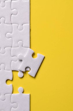 Sarı arka planda beyaz yapboz parçaları. Düz yatıyordu. Üst görünüm