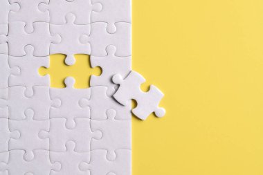 Sarı arka planda beyaz yapboz parçaları. Düz yatıyordu. Üst görünüm