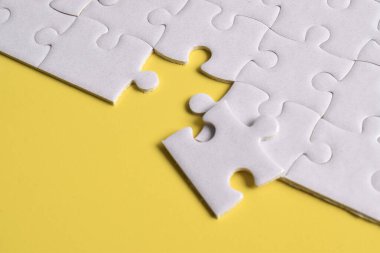 Sarı arka planda beyaz yapboz parçaları. Üst görünüm