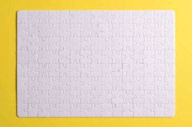 Sarı arka planda beyaz yapboz parçaları. Düz yatıyordu. Üst görünüm