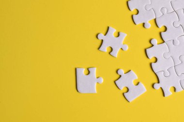 Sarı arka planda beyaz yapboz parçaları. Metin için boşluk kopyala, üst görünüm.