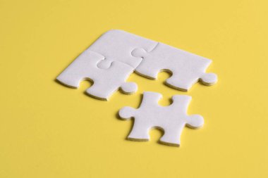 Sarı arka planda dört yapboz parçası. Takım çalışmasında doğru çözümleri bulma kavramı.