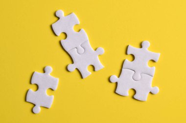 Sarı arkaplanda beyaz yapboz parçaları, üst görünüm