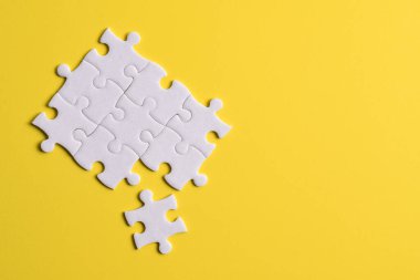 Sarı arka planda beyaz yapboz parçaları. Metin için boşluk kopyala, üst görünüm.