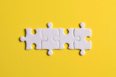 Sarı arka planda dört yapboz parçası. Takım çalışmasında doğru çözümleri bulma kavramı.