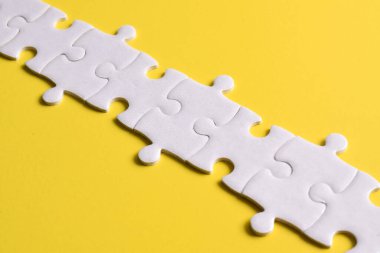 Beyaz yapboz parçaları sarı arkaplanda bir çizgi oluşturuyor