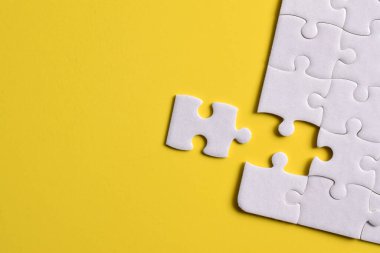 Sarı arka planda beyaz yapboz parçaları. Düz yatıyordu. Üst görünüm