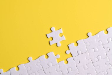 Sarı arka planda beyaz yapboz parçaları. Metin için boşluk kopyala, üst görünüm.