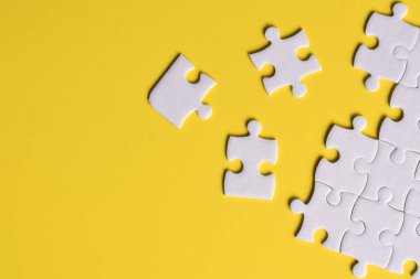 Sarı arka planda beyaz yapboz parçaları. Metin için boşluk kopyala, üst görünüm.