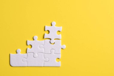 Sarı arka planda beyaz yapboz parçaları. Metin için boşluk kopyala, üst görünüm.