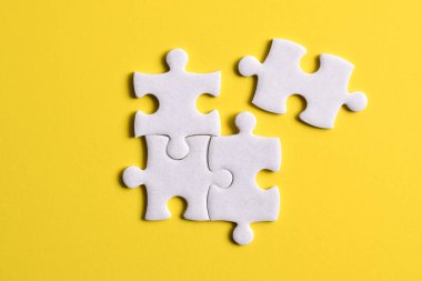 Sarı arka planda dört yapboz parçası. Takım çalışmasında doğru çözümleri bulma kavramı.