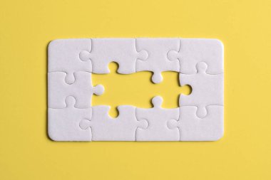 Sarı arka planda beyaz yapboz parçaları. Düz yatıyordu. Üst görünüm