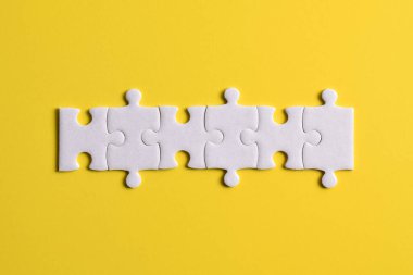 Beyaz yapboz parçaları sarı arkaplanda bir çizgi oluşturuyor
