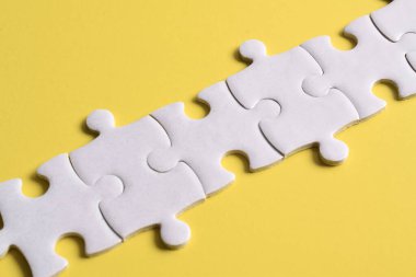 Beyaz yapboz parçaları sarı arkaplanda bir çizgi oluşturuyor