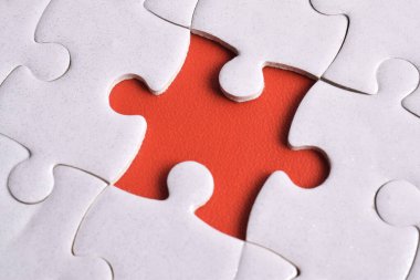 Kırmızı arkaplanda eksik parçalı beyaz bulmaca, yakın plan