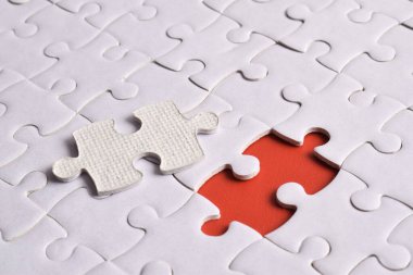 Kırmızı arkaplanda eksik parçalı beyaz bulmaca, yakın plan