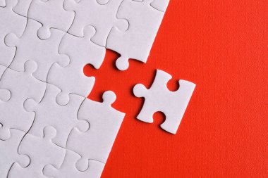 Kırmızı arka planda beyaz yapboz parçaları. Düz yatıyordu. Üst görünüm