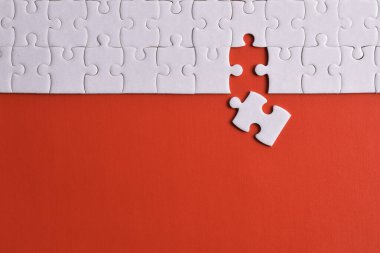 Kırmızı arka planda beyaz yapboz parçaları. Düz yatıyordu. Üst görünüm