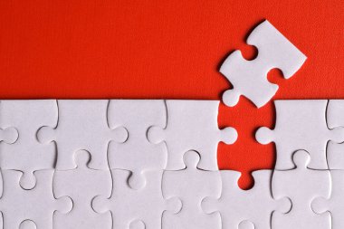 Kırmızı arka planda beyaz yapboz parçaları. Düz yatıyordu. Üst görünüm