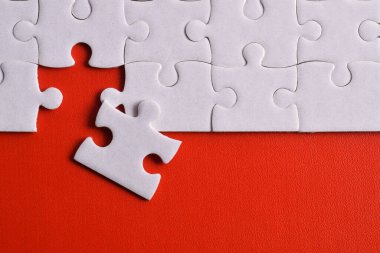 Kırmızı arka planda beyaz yapboz parçaları. Düz yatıyordu. Üst görünüm